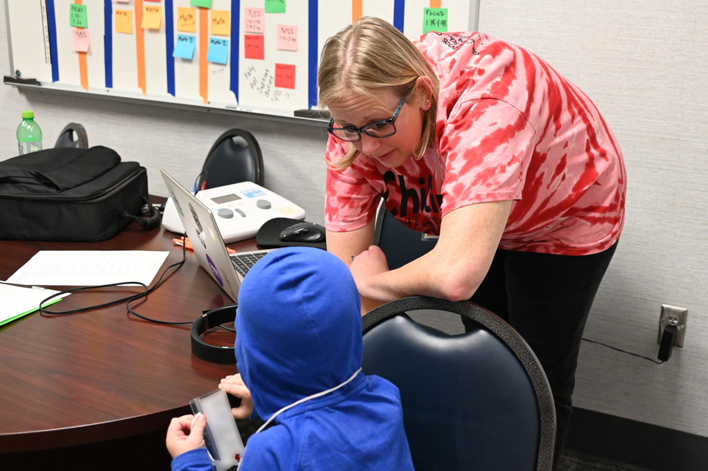 woman leaning over talking to a child wearing a blue hoodie