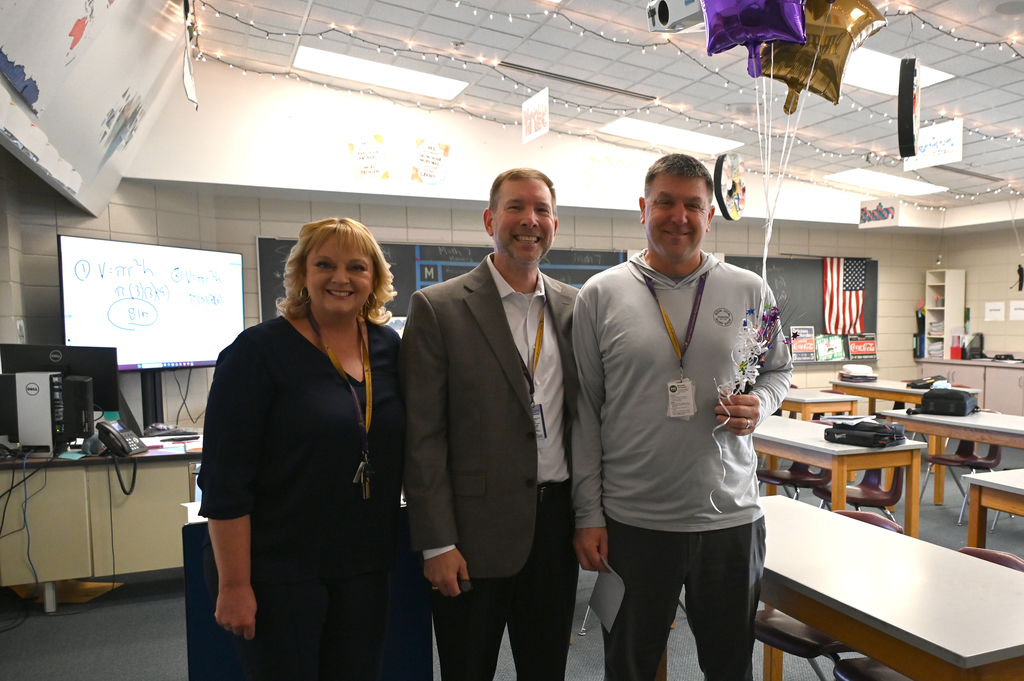 two men and a woman standing side by side smiling at camera