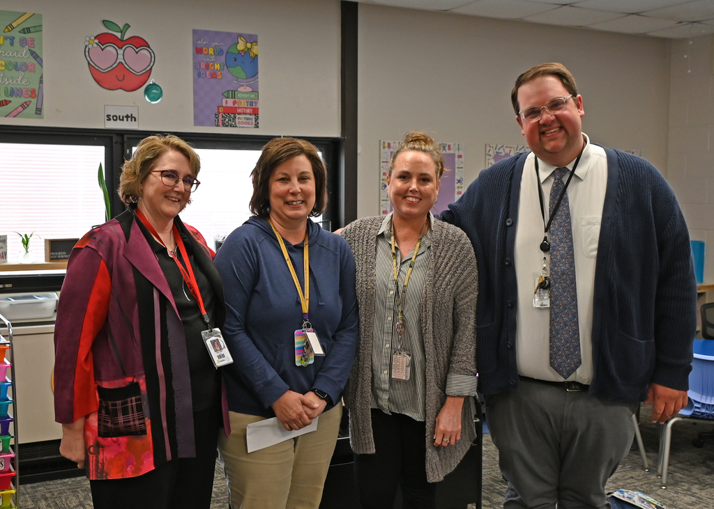 four adults standing in line smiling