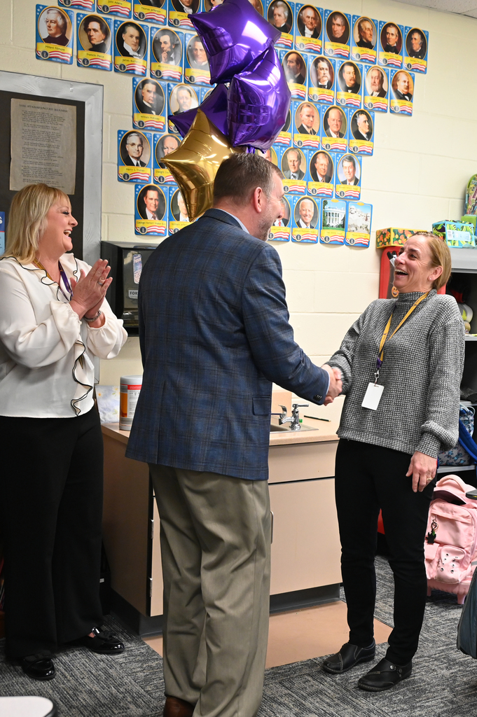 woman smiling as she shakes hand and anther woman cheers
