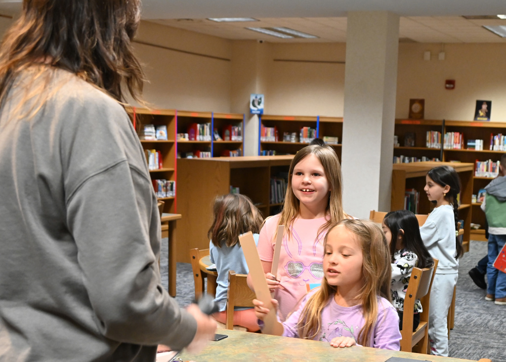 children standing in line at a library talking to librarian