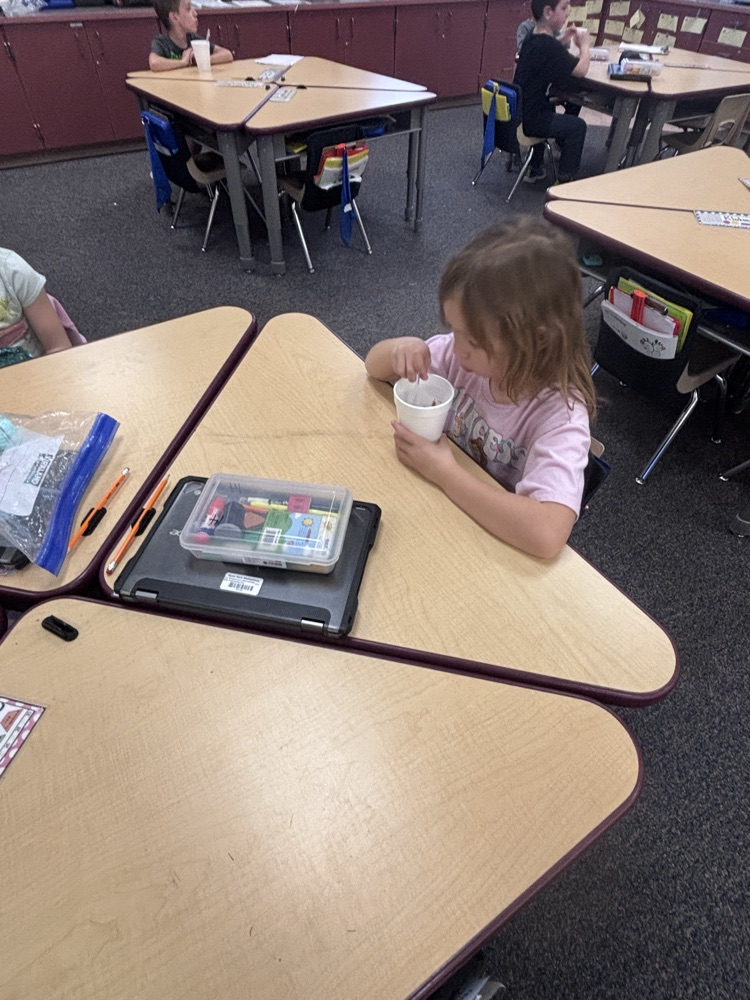 Student eating our of a cup at a school desk
