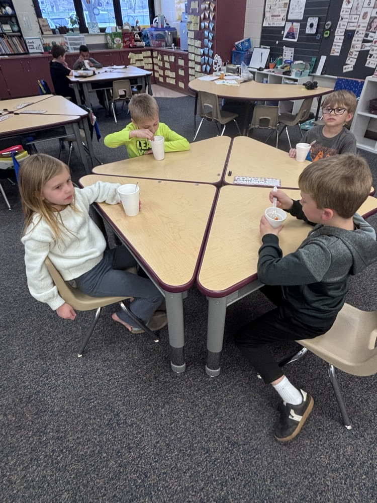 Students at desks eating out of cups