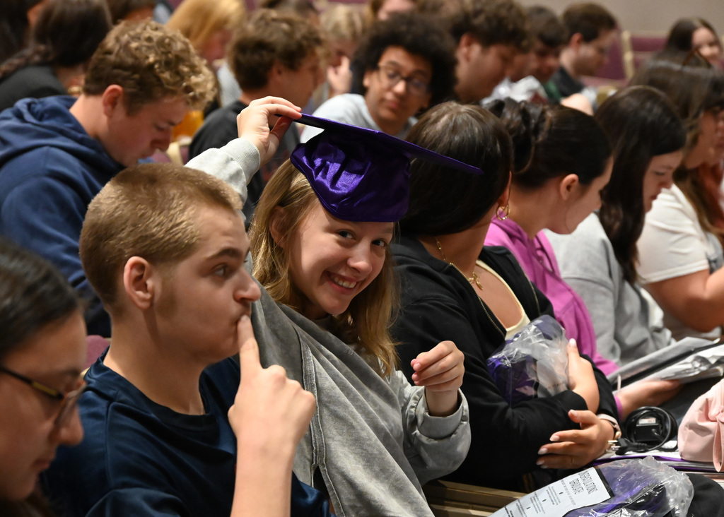 Girl trying out graduation cap in group of other students