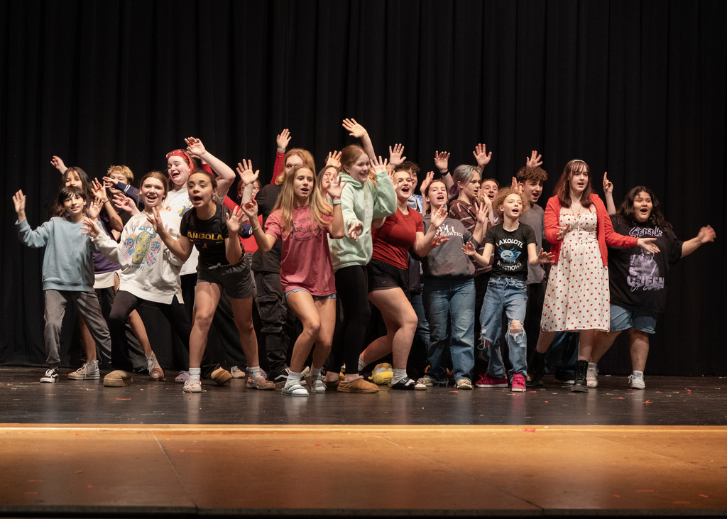 Large group of people in huddle showing jazz hands