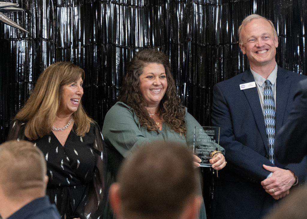 women holding award with a person on each side posing for a photo