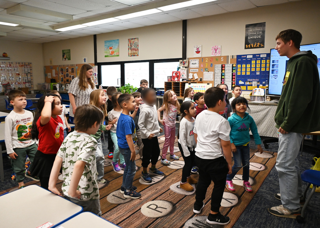 childern standing together following actions of person in front of room