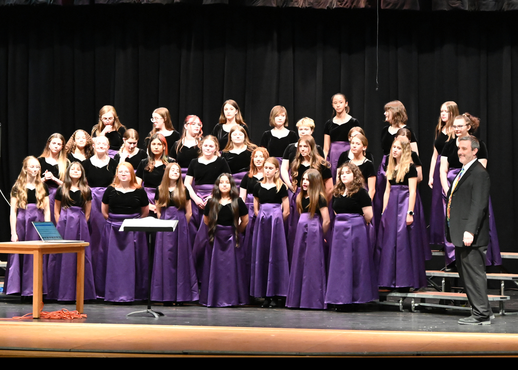 choir of girls dressed in black and purple dresses singing