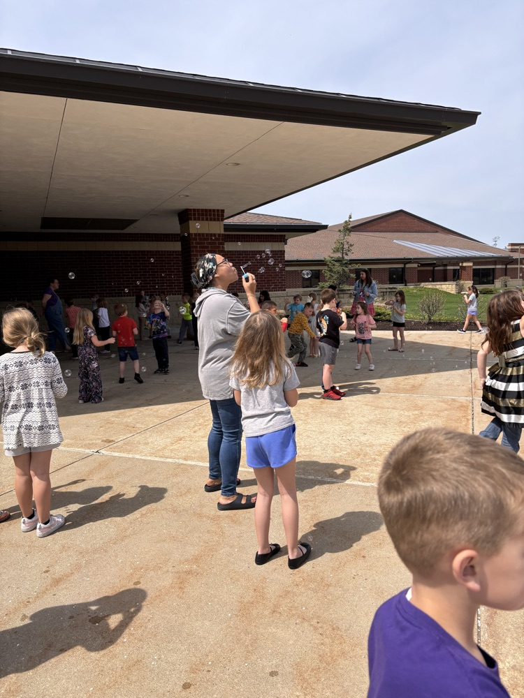 teacher and child blowing bubbles outsides