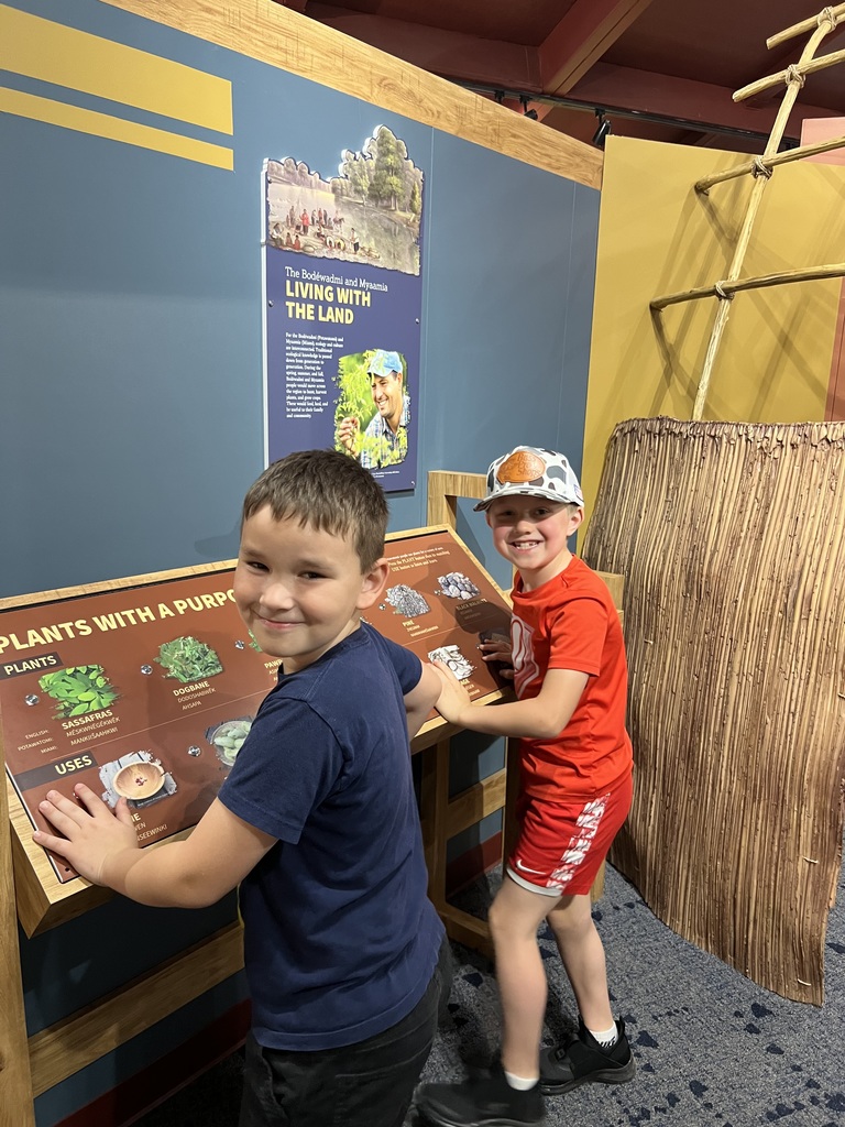 two boys in front of a display looking at camere