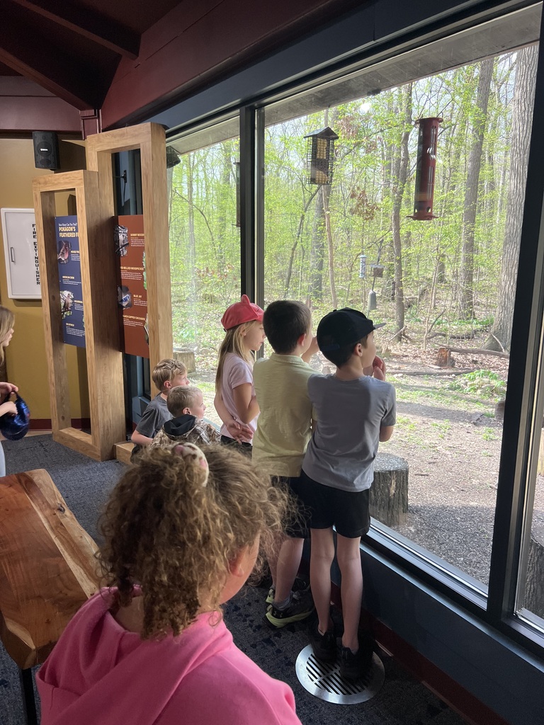 children standing in front of very large window looking out