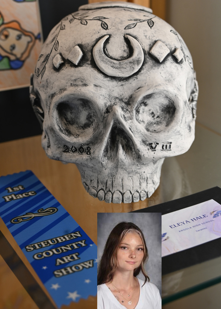 a clay skull white with designs, 1st place ribbon, picture of artist.