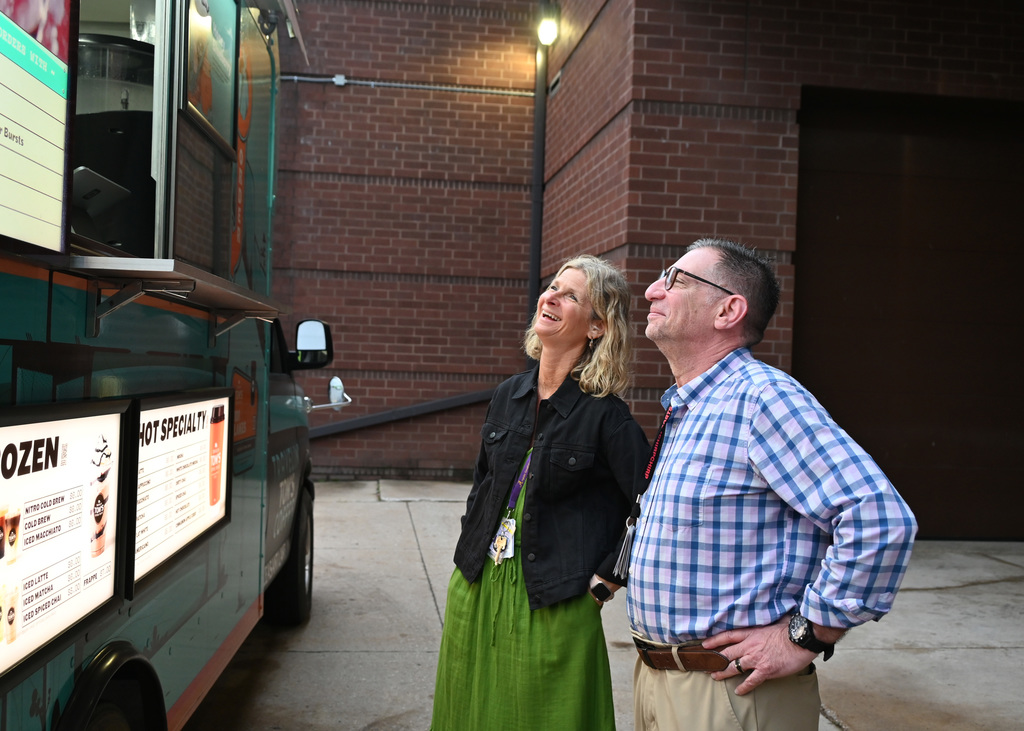 a man and women standing in front of coffee truck smiling