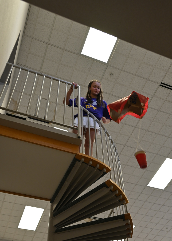  a student drops a hand make parachute from top of flight of stairs