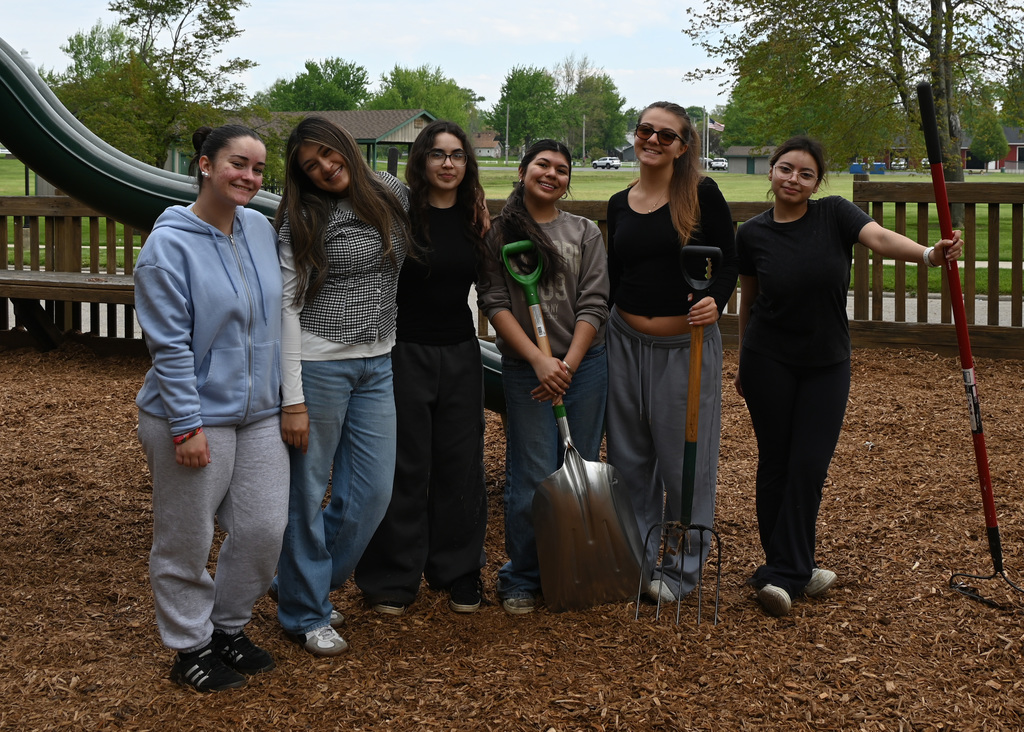 6 girls posing for photo a couple holding shovels and rakes