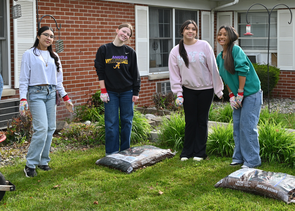 four teenage girls posing for picture in a garden