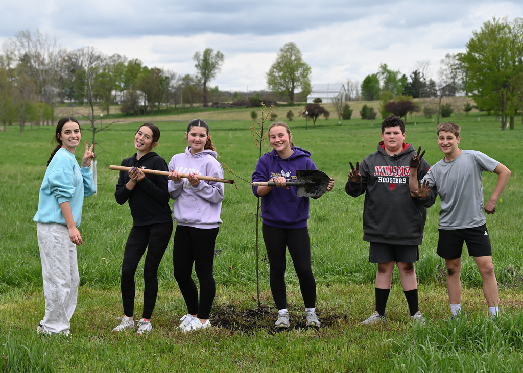 Six middle school students posing for a picture showing dirty hand and shovel