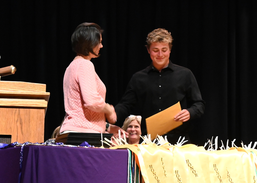 boy shaking hands with woman as he is handed a certificate