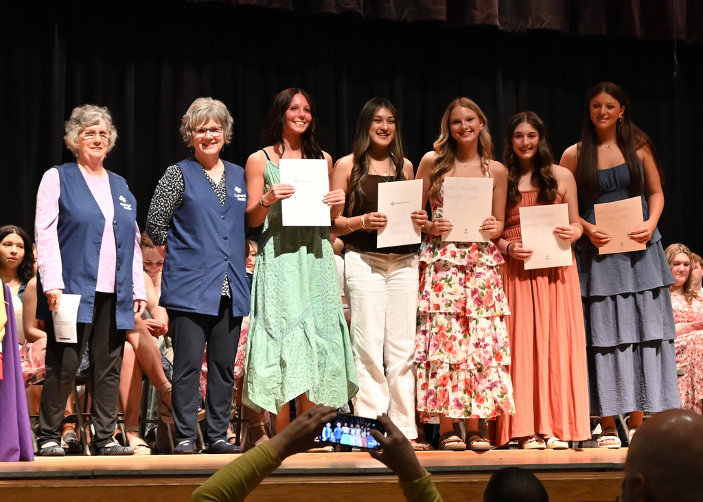 two woman stand with 5 girls holding up certificates