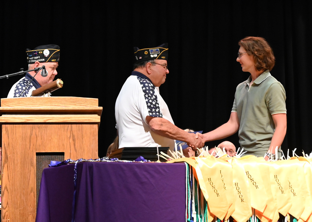 boy shaking hands with man as he is handed a certificate, anothr man looks on