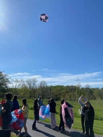Students standing watching air balloon ash they hold thier uninflated balloons