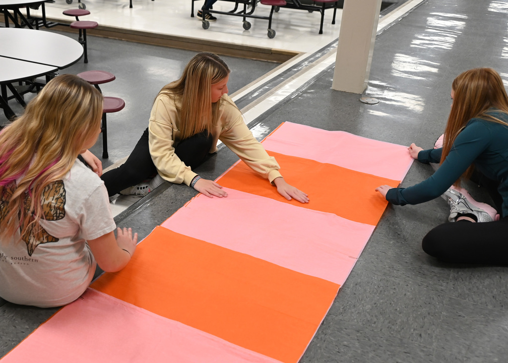 girls measuring long sheets of paper