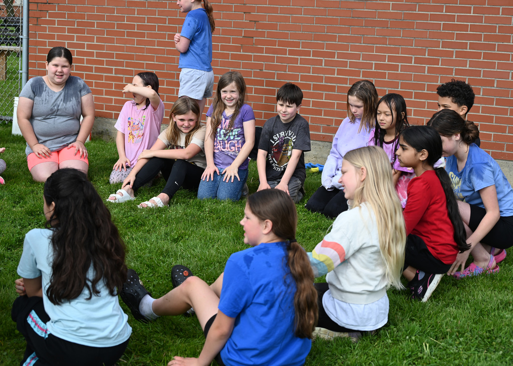 fourth grade students sitting in a circli in ghe grass