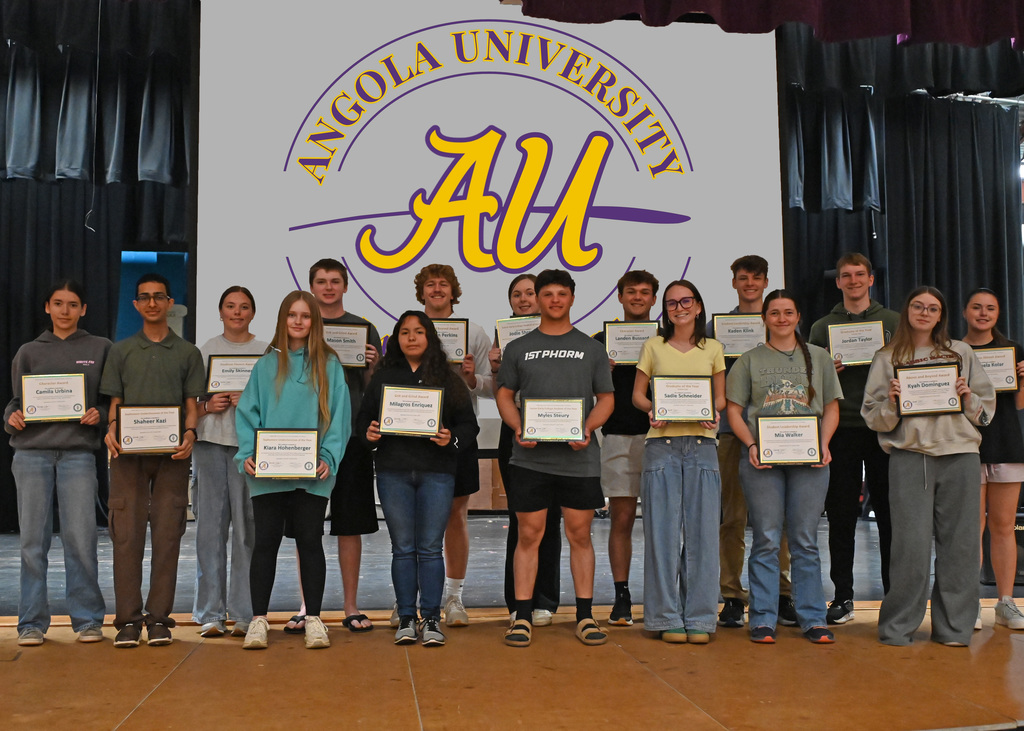 16 high school students posing for picture holding plaques in front of angola Univestiy sign