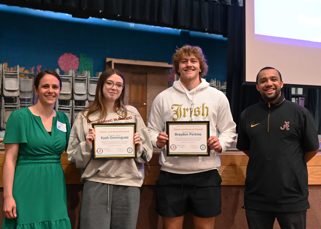 two student hold awards with a teacher on each side