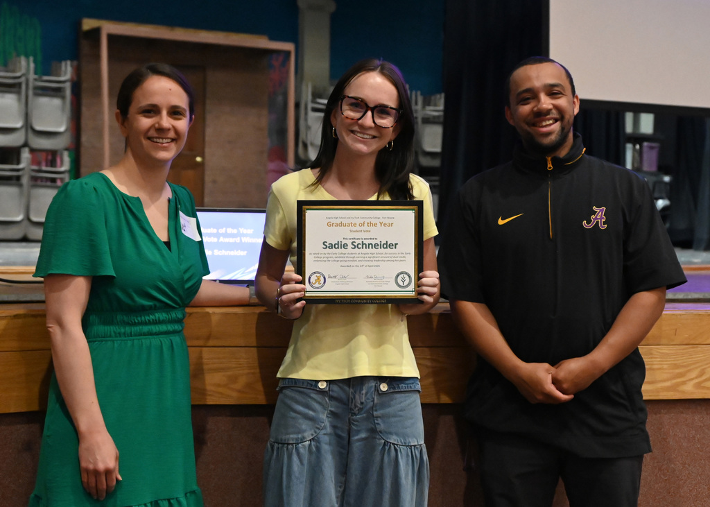 student hold awards with a teacher on each side