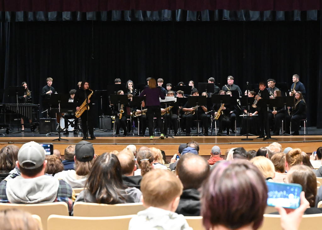 Middle school jazz band on stafe with saxapone and trumpet on each side playine solos