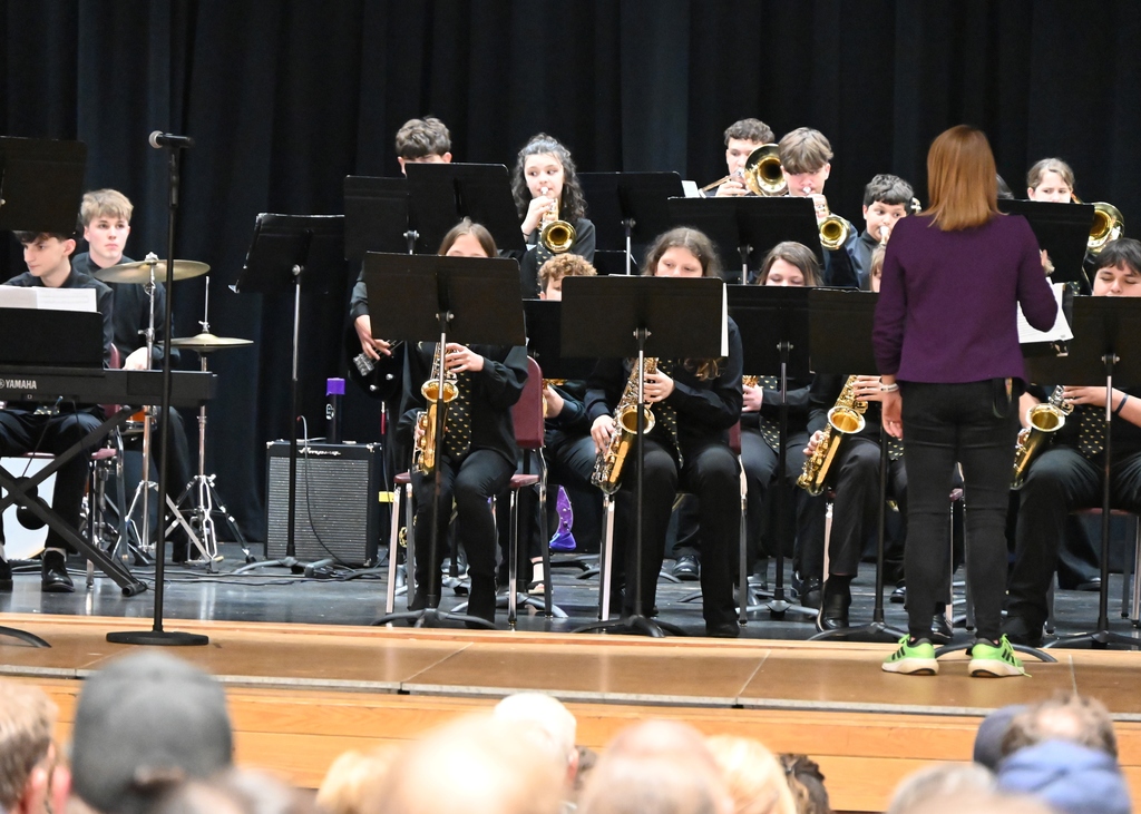 Middle school jazz band students playing a concert aon stage can see saxaphones and trumpets