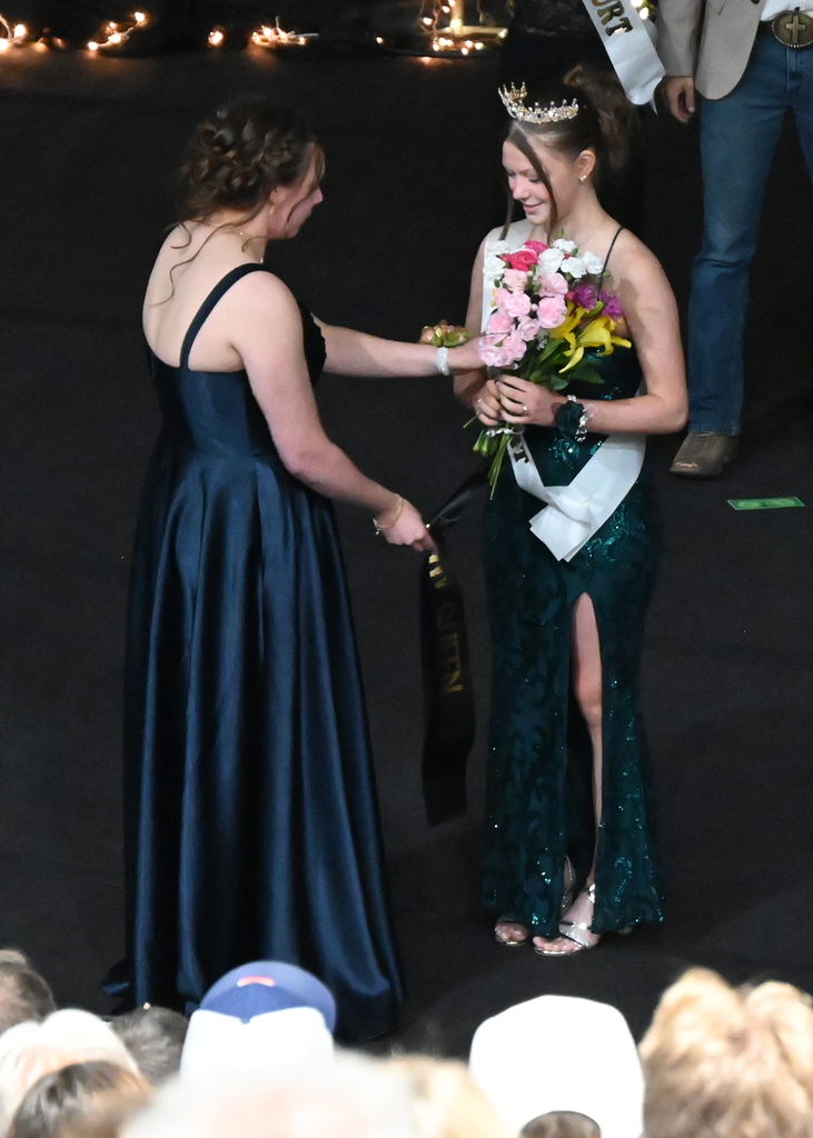 girls in prom dresson one giving the other flowers
