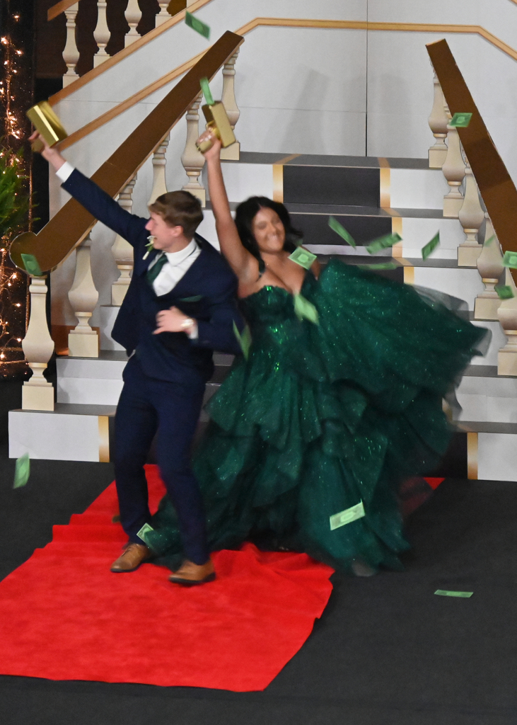 girl in green dress boy in tux dancing with money guns