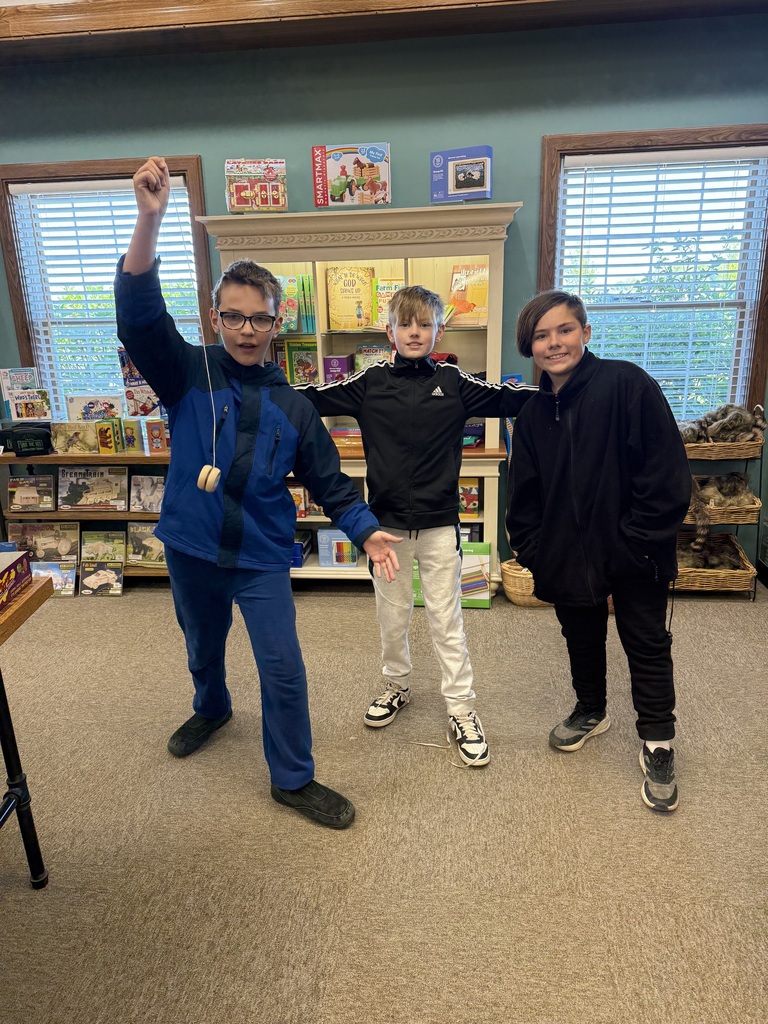 .thre boys one standig in a row one showing off a YoYo