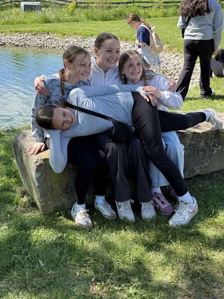 4 Girls three sitting on a large stone one laid across their laps all are smilling