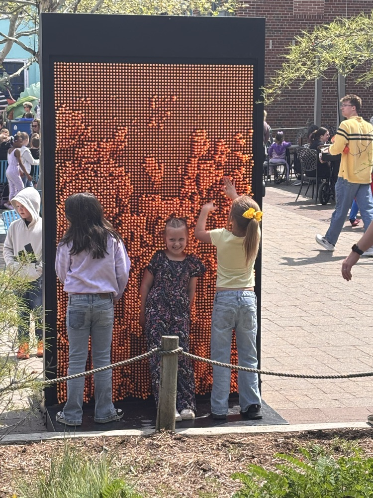 Three girls in front of giant pin board