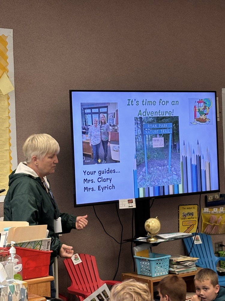 woman in standing next to large TV tha has guide information
