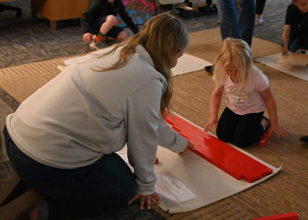 woman and child on floor playing with a block game