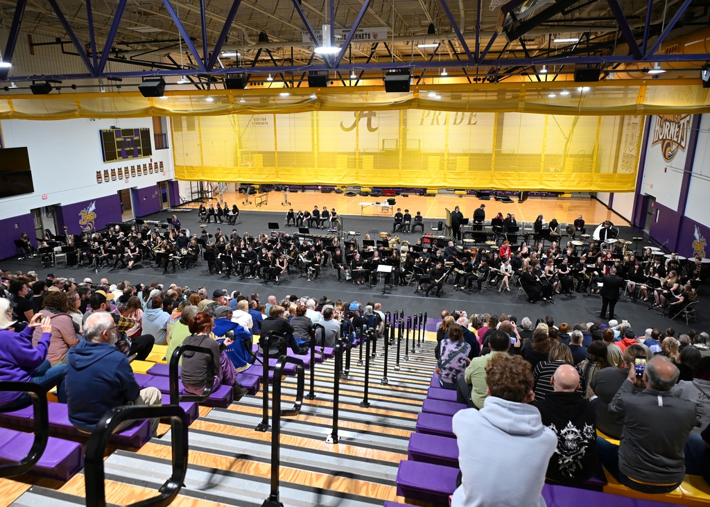 middle school and high school bands on gym floor giving concert to bleachers full of fans