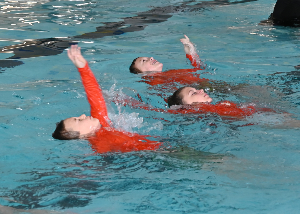 3 kids doing bakc stroke in pool