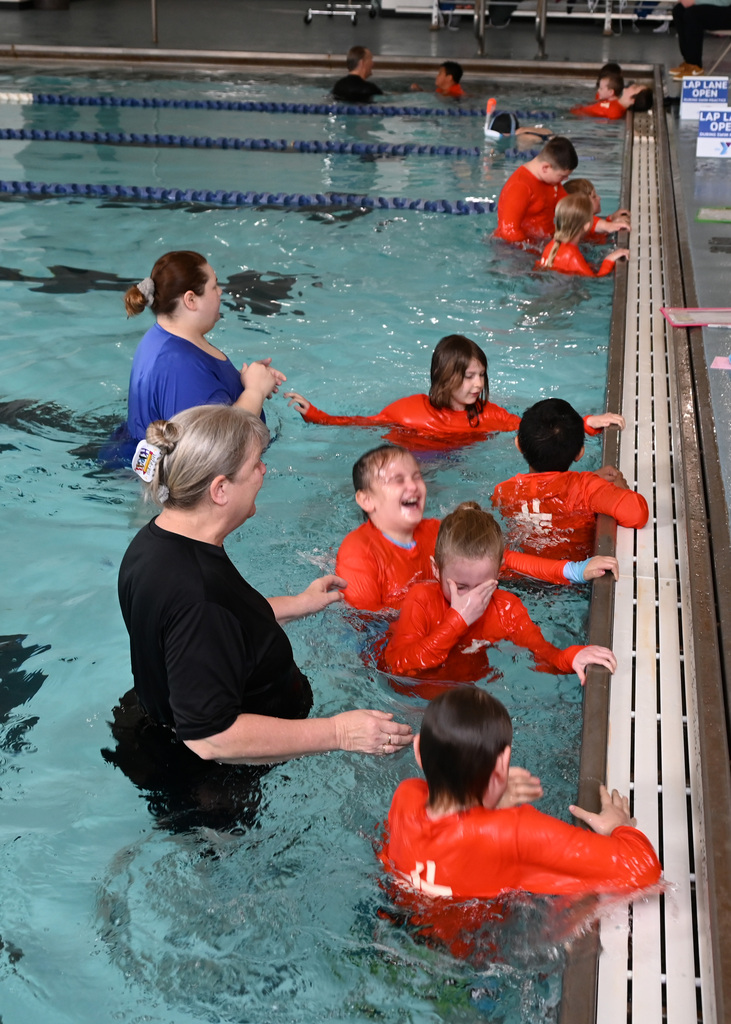 groups of students hanging on to pool edge for swimming lessons