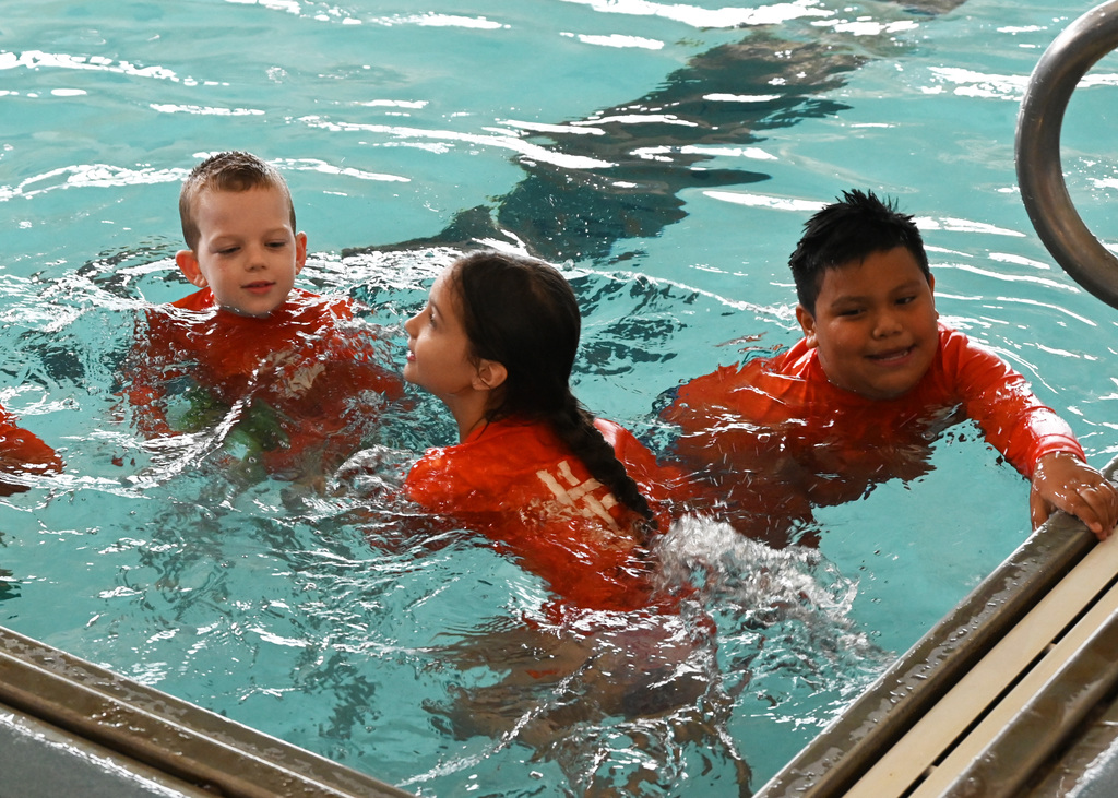 three children playing in a pool