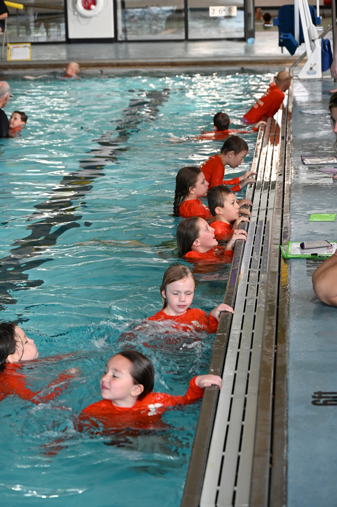 line of kids hangin on pool edge