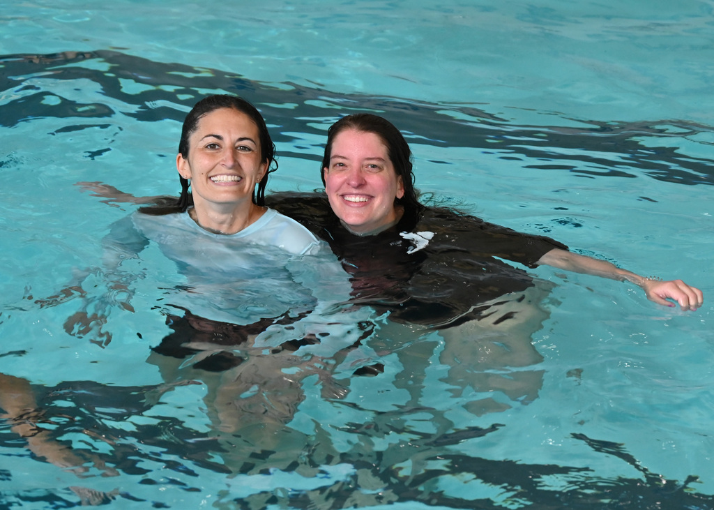 Two women in pool looking at camera smiling