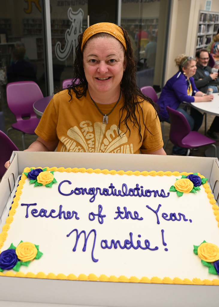 Woman with a cake that says congratulations teacher of the year Mandie