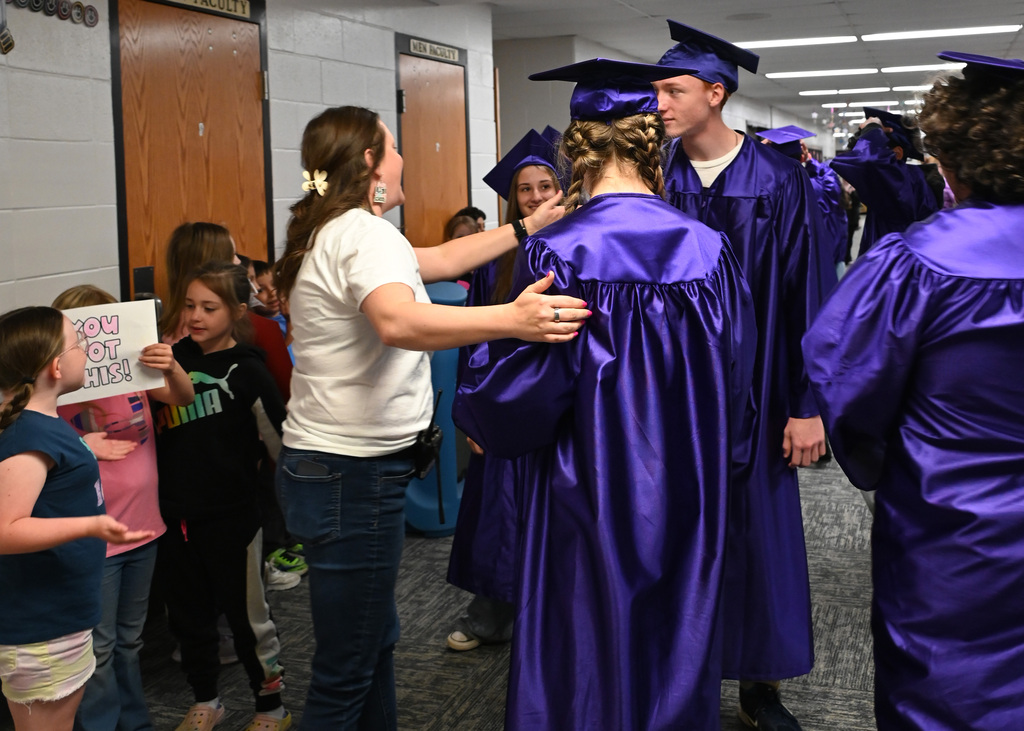 woman hugging students in caps and gowns