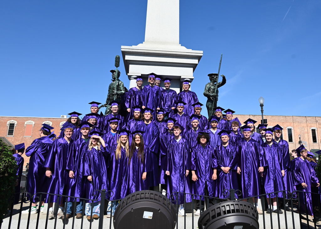 very large group of students in caps and gowns standing in front of monument