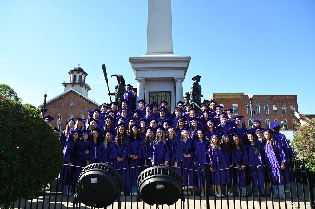 very large group of students in caps and gowns standing in front of monument