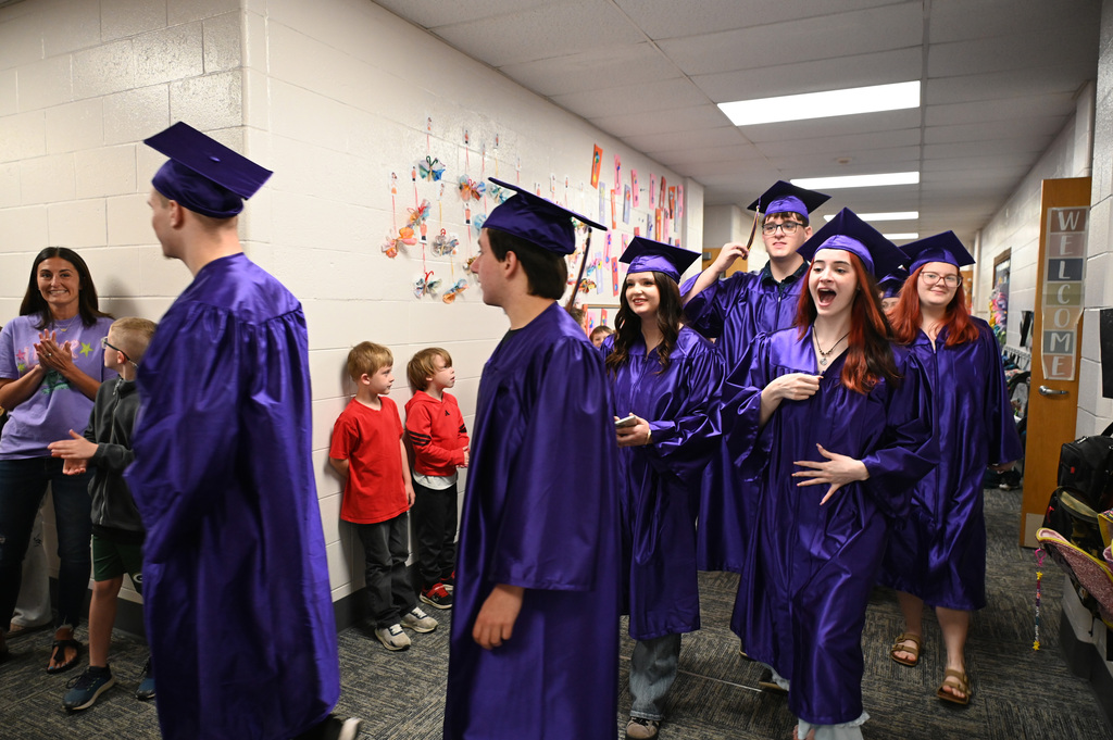 students in caps and gowns waliking down a hallway